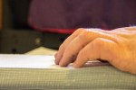 A close up of hands reading a braille page.