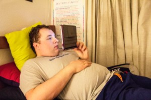 A man lays on a bed while looking at an iPad.